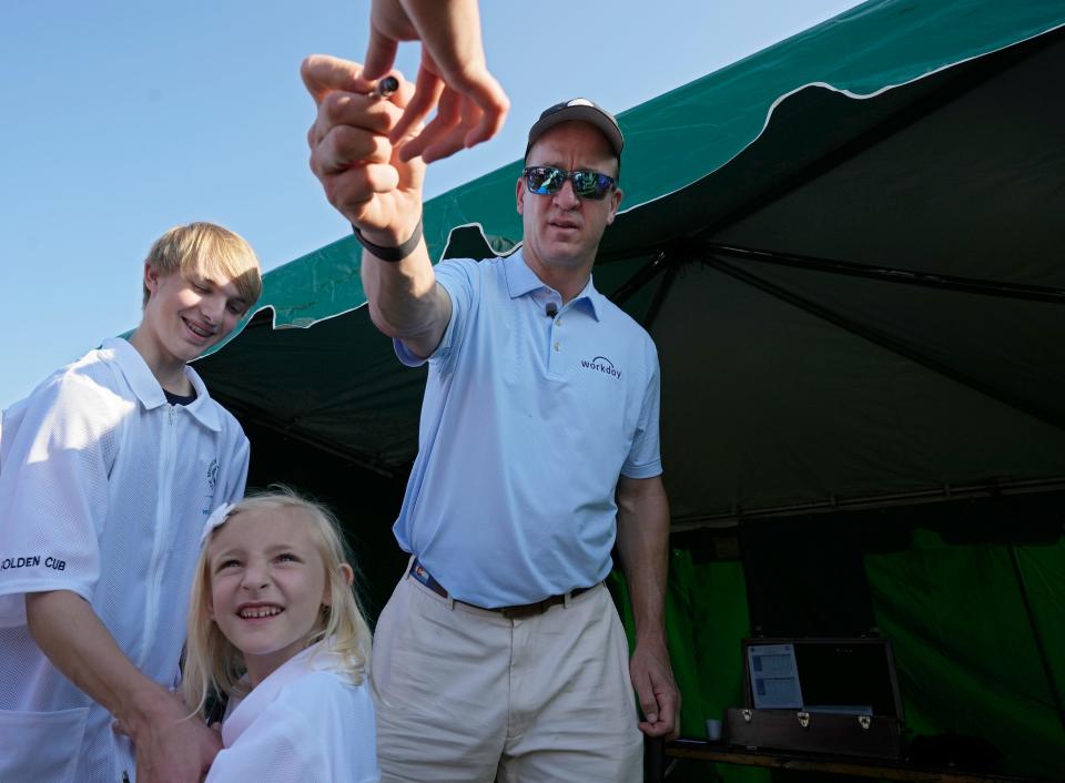 Former NFL quarterback Peyton Manning hands back a marker after signing the jerseys of Amelia, 6, and Reid Zupanc, 15, of Delaware, during the Golden Bear Pro-Am at the Memorial Tournament.