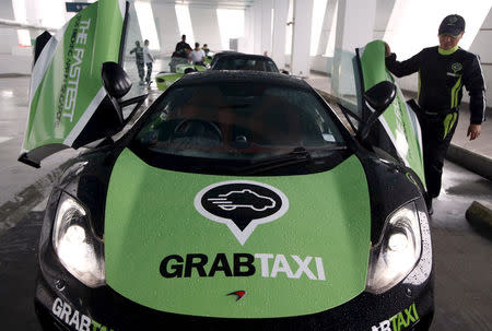 A driver checks his McLaren taxi after a photoshoot for taxi-booking app GrabTaxi's fleet of seven luxury cars in Singapore September 15, 2015. REUTERS/Edgar Su/File Photo