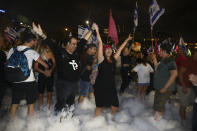 Israelis celebrate the swearing in of the new government in Tel Aviv, Israel, Sunday, June 13, 2021. Israel's parliament has voted in favor of a new coalition government, formally ending Prime Minister Benjamin Netanyahu's historic 12-year rule. Naftali Bennett, a former ally of Netanyahu became the new prime minister. (AP Photo/Oded Balilty)