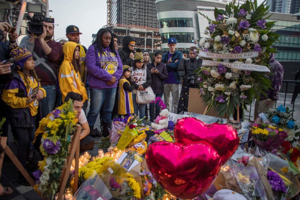 People gather around a makeshift memorial for former NBA and Los Angeles Lakers player Kobe Bryant after learning of his death, at LA Live plaza in front of Staples Center in Los Angeles on January 26, 2020. - Nine people were killed in the helicopter crash which claimed the life of NBA star Kobe Bryant and his 13 year old daughter, Los Angeles officials confirmed on Sunday. Los Angeles County Sheriff Alex Villanueva said eight passengers and the pilot of the aircraft died in the accident. The helicopter crashed in foggy weather in the Los Angeles suburb of Calabasas. Authorities said firefighters received a call shortly at 9:47 am about the crash, which caused a brush fire on a hillside. (Photo by Apu GOMES / AFP) (Photo by APU GOMES/AFP via Getty Images)