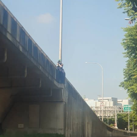 員警跨坐在匝道口的護欄旁值勤。（圖／翻攝自記者爆料網臉書）