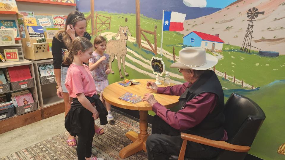 John Erickson, author of "Hank the Cowdog," signs a book for fans Thursday at the Burrowing Owl bookstore in Amarillo.