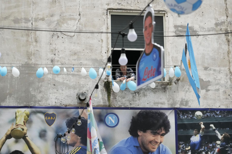 Una mujer observa desde su ventaja los globos desinflados con los colores del Napoli, el lunes 1 de mayo de 2023, en Nápoles. (AP Foto/Gregorio Borgia)