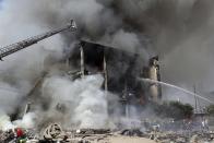 Firefighters extinguish flames as smoke rises from Surmalu market about two kilometers (1.2 miles) south of the center of Yerevan, Armenia, Sunday, Aug. 14, 2022. A strong explosion at a fireworks storage area has ripped through a market in Armenia's capital. At least one person has been killed and about 20 others have been injured. The blast on Sunday set off a large fire. (Vahram Baghdasaryan/Photolure via AP)