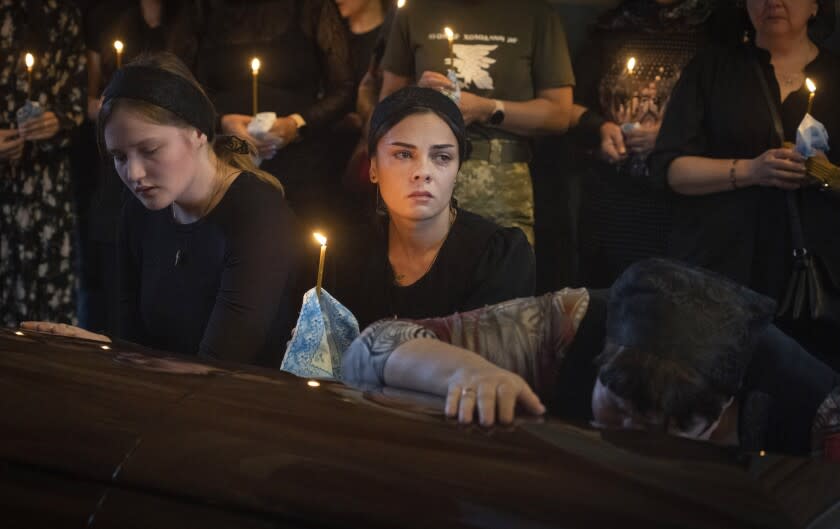 Relatives mourn at the coffin of a soldier, codename Fanat, killed by the Russian troops in a battle during a ceremony at St Michael cathedral in Kyiv, Ukraine, Ukraine, Monday, July 18, 2022. (AP Photo/Efrem Lukatsky)