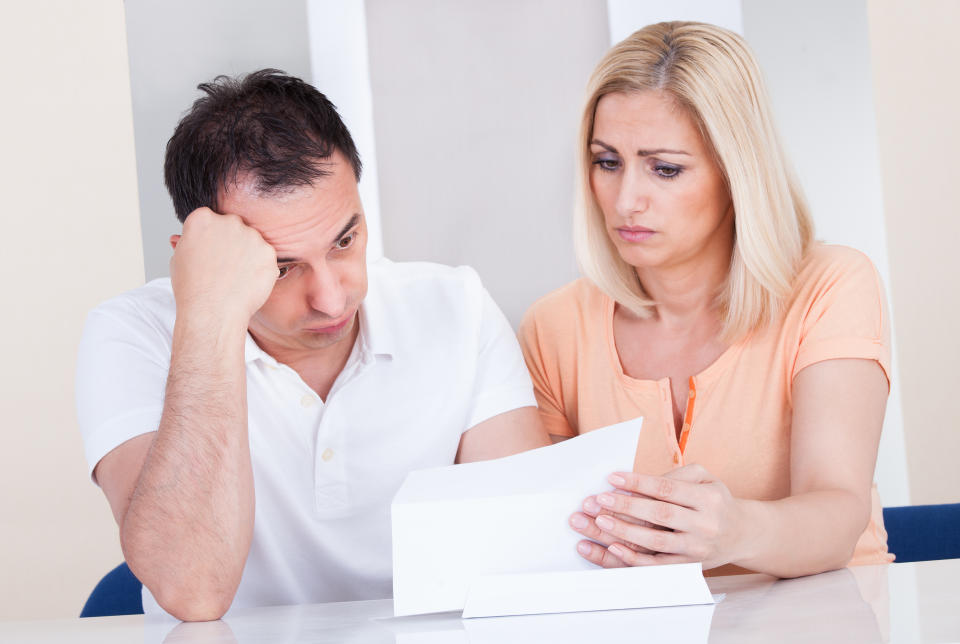 Couple with unhappy expressions looking at document