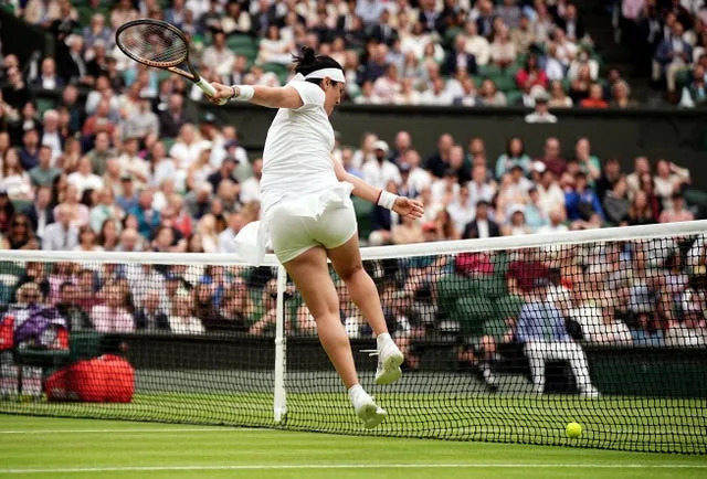 Ons Jabeur kicks the tennis ball at the net in frustration