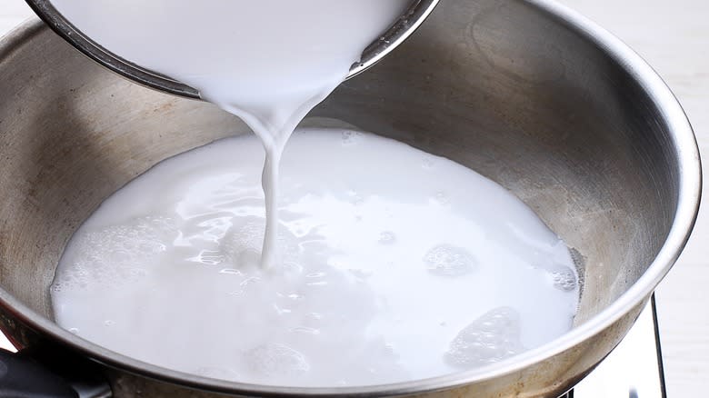 Pouring coconut milk into a metal bowl