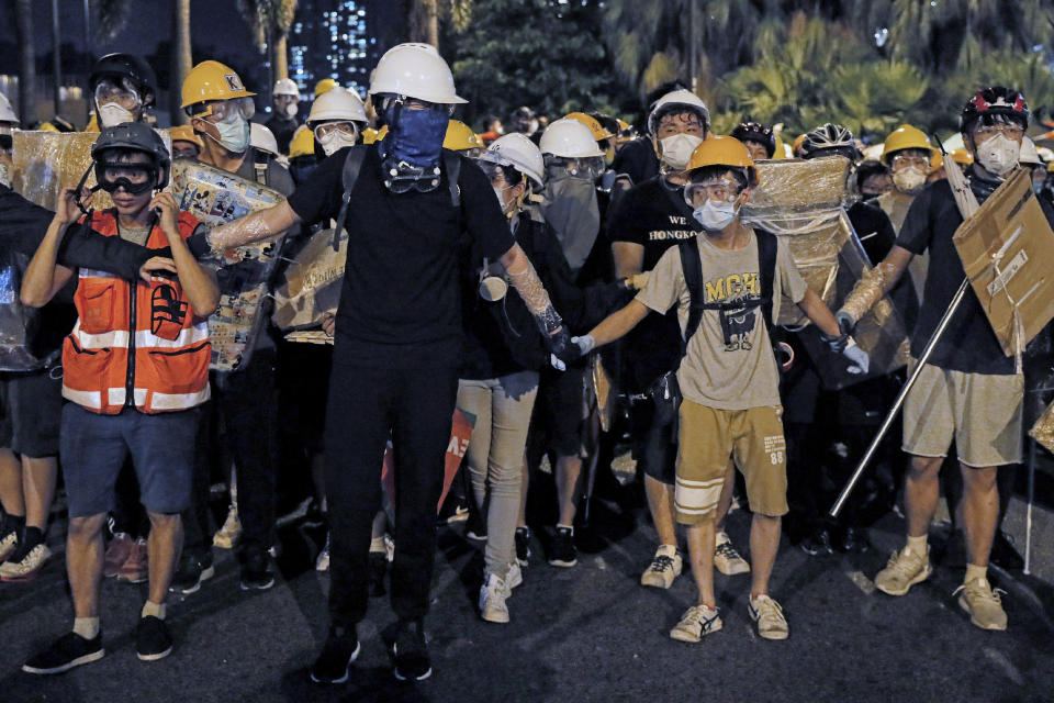 In this Sunday, July 14, 2019, photo, protesters wearing protection gears as they prepare to face-off with policemen on a street in Sha Tin District in Hong Kong. What began as a protest against an extradition bill has ballooned into a fundamental challenge to the way Hong Kong is governed _ and the role of the Chinese government in the city’s affairs. (AP Photo/Kin Cheung)