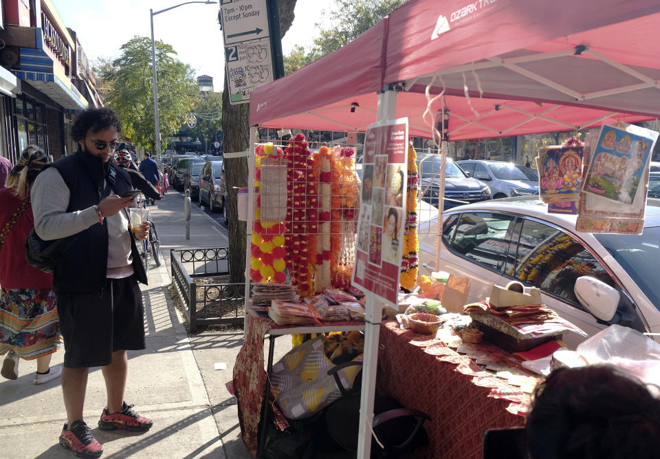 Pratik Shetty, son of the proprietor of Flowers by Bhanu, stands by their Diwali stall, which offers flowers, stickers and other Diwali items in the Jackson Heights section in the Queens borough of New York on Oct. 22, 2022. (AP Photo/Mallika Sen)