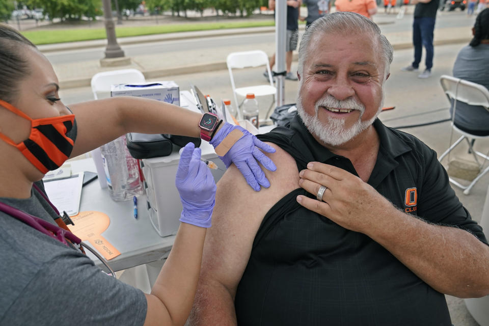 Mick Mitchell, of Edmond, Okla., smiles as he gets a COVID-19 vaccination shot from Dondie Hess, left, of the Oklahoma State University Center for Health Sciences, at a vaccination event before an NCAA college football game between Missouri State and Oklahoma State, Saturday, Sept. 4, 2021, in Stillwater, Okla. Oklahoma State University announced that it will host COVID-19 vaccine clinics before home football games this fall to make it easier for students, fans and the community to receive a vaccine. (AP Photo/Sue Ogrocki)