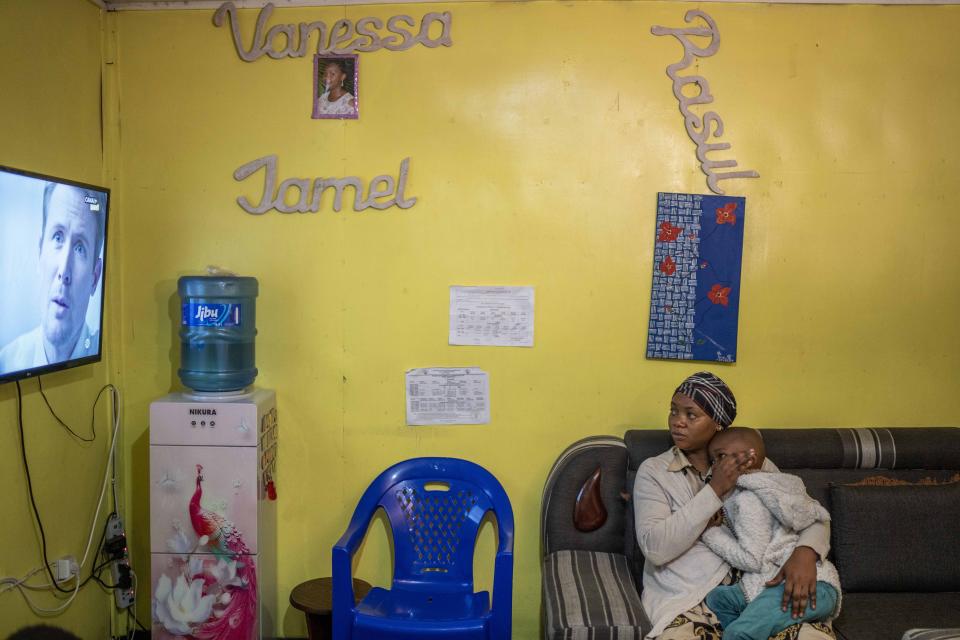 Vanessa Emedy holds her son as they watch television in Goma, Democratic Republic of the Congo, Tuesday March 29, 2022. The night of Emedy's husband Godefroid Kamana's burial, extended family members came to the family home where Vanessa had just begun her period of mourning. "They didn't wait the 40 days," she lamented. "I was stripped of everything, of all my possessions." (AP Photo/Jerome Delay)