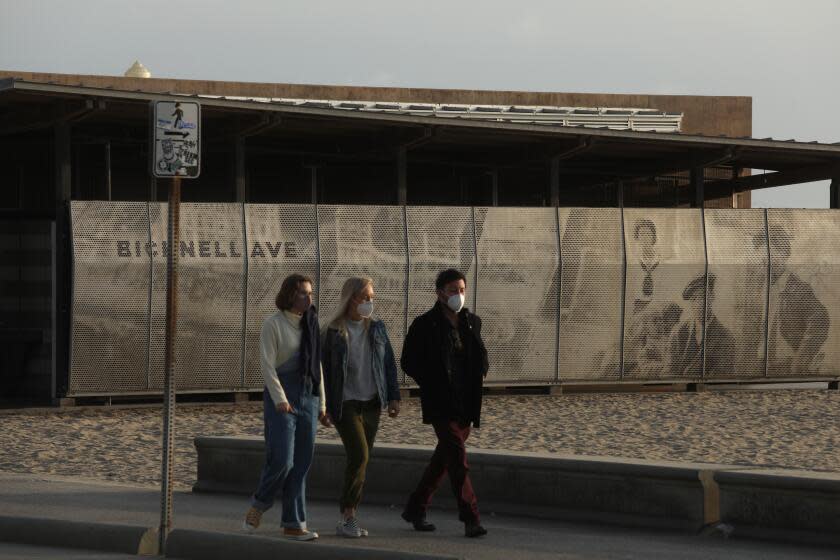 SANTA MONICA, CA - FEBRUARY 9, 2021 - - People walk along a pedestrian path in Santa Monica on February 9, 2021. In the background is a mural which features African Americans enjoying the beach at the site in the early 1900's. The beach at Bay Street ending to Bicknell Avenue was once referred derogatorily, "The Inkwell," by nearby Anglos in reference to African American beach-goers from 1905 to 1964. (Genaro Molina / Los Angeles Times)