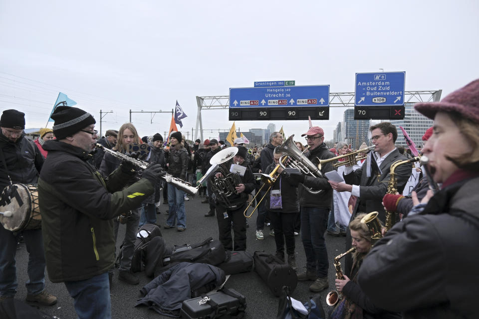 A band plays while climate activists block the main highway around Amsterdam near the former headquarters of a ING bank to protest its financing of fossil fuels, Saturday, Dec. 30, 2023. Protestors walked onto the road at midday, snarling traffic around the Dutch capital in the latest road blockade organized by the Dutch branch of Extinction Rebellion. (AP Photo/Patrick Post)