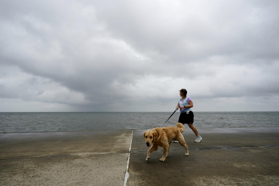 Jane McDow walks with her dog 'Duke' along the Lake Pontchartrain seawall in New Orleans, Wednesday, Oct. 28, 2020. Hurricane Zeta is expected to make landfall this afternoon as a category 2 storm. (AP Photo/Gerald Herbert)