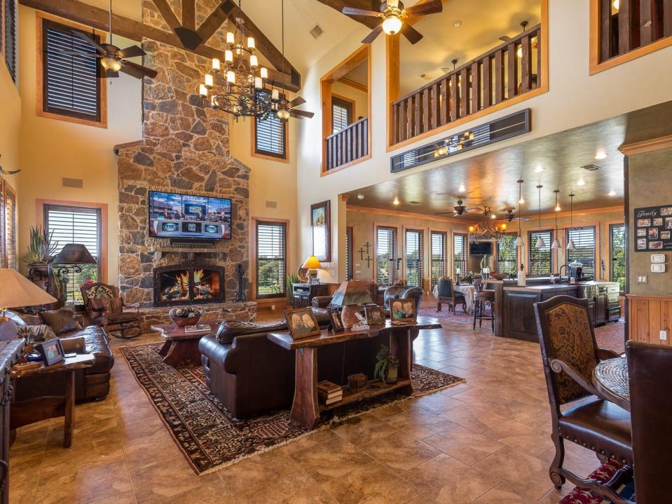 Interior photo of Terry Bradshaw's home shows leather couches, a balcony, and stone chimney in the living room.