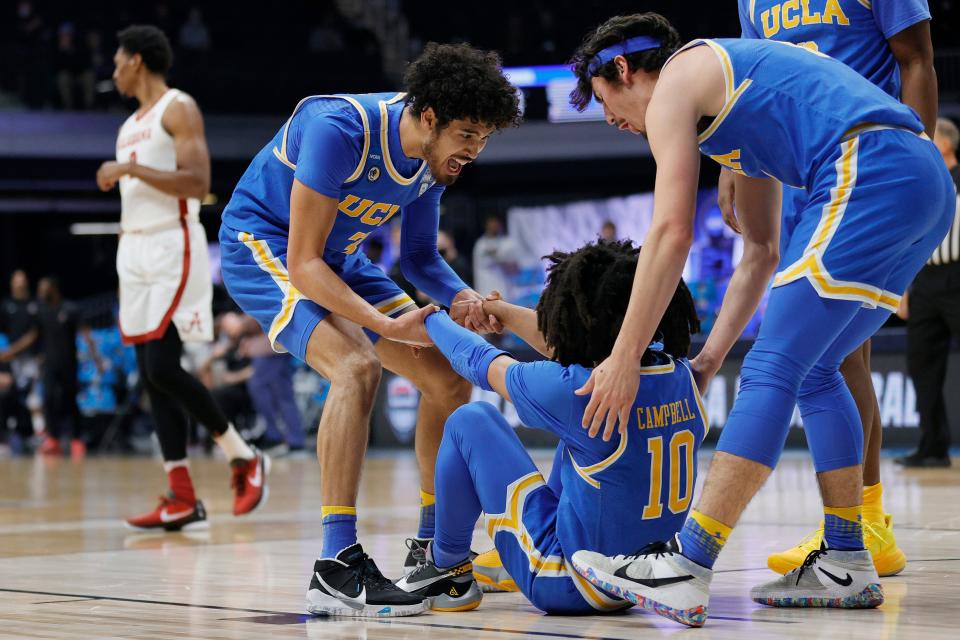 Tyger Campbell of the UCLA Bruins celebrates with Johnny Juzang and Jaime Jaquez Jr. against the Alabama Crimson Tide during the first half in the Sweet Sixteen round game of the 2021 NCAA Men's Basketball Tournament at Hinkle Fieldhouse.