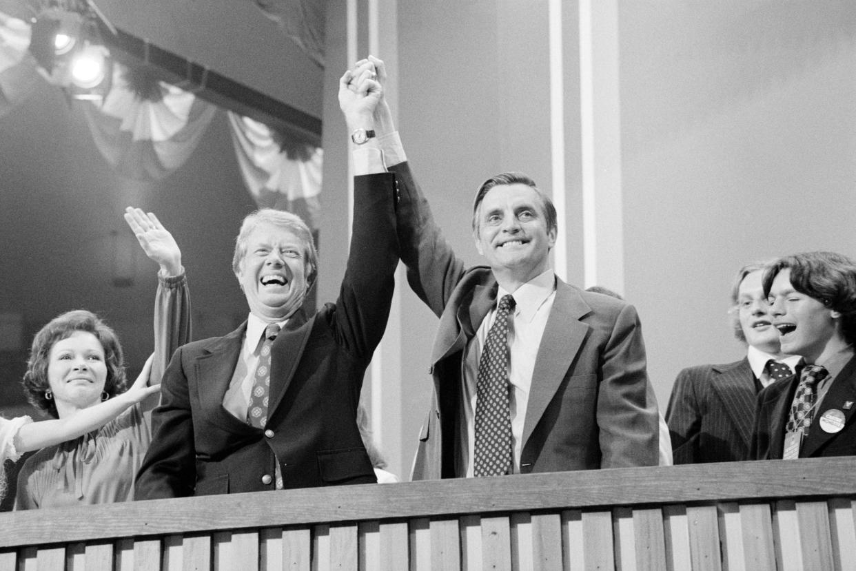 Jimmy Carter and Walter Mondale clasp hands over their heads in a black and white picture from 1976.