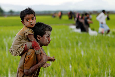 A Rohingya boy carries a child after after crossing the Bangladesh-Myanmar border in Teknaf, Bangladesh, September 1, 2017. REUTERS/Mohammad Ponir Hossain