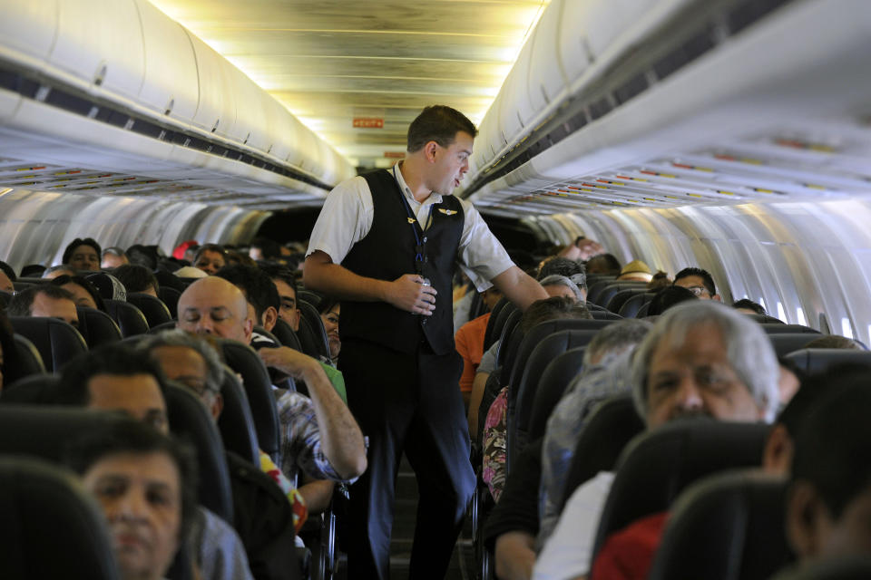 In this Thursday, May 9, 2013, photo, Allegiant Air flight attendant Chris Killian prepares his passengers for the Laredo, Tex, bound flight before it pushes back from the terminal at McCarran International Airport in Las Vegas. While other U.S. airlines have struggled with the ups and downs of the economy and oil prices, tiny Allegiant Air has been profitable for 10 straight years. (AP Photo/David Becker)