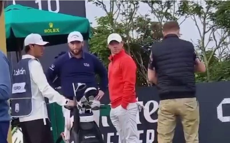 a spectator comes on and takes McIlroy's club and then the players all look shocked., , Screengrabs from video on https://www.instagram.com/golfmagic/ - Scottish Open hit by bizarre incident as spectator takes club out of Rory McIlroy's bag at tee box - INSTAGRAM.COM/GOLFMAGIC