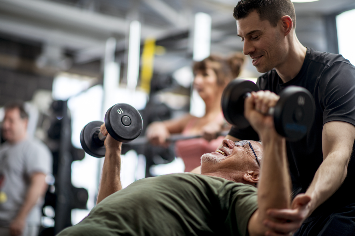Trainer talking to a man lifting dumbbells