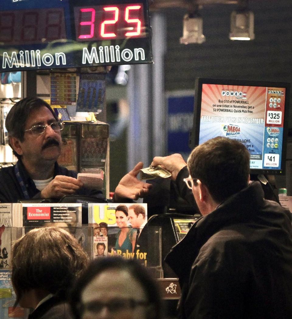A vendor, left, receives money for a lottery purchase on Friday, Nov. 23, 2012 in New York. The jackpot for Powerball's weekend drawing has climbed to $325 million, the fourth-largest in the game's history. Powerball organizers say this is the first run-up to a large jackpot that's fallen over a major holiday. (AP Photo/Bebeto Matthews)