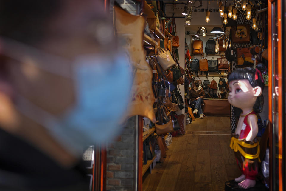 Un hombre con mascarilla pasa caminando frente a una tienda de bolsos de moda en una calle comercial turística en Beijing, el miércoles 1 de marzo de 2023. La agenda del presidente chino Xi Jinping para la reunión anual del órgano legislativo ceremonial: Reactivar la maltrecha economía animando a los consumidores a gastar ahora que han finalizado los severos controles antivirus. (AP Foto/Andy Wong)