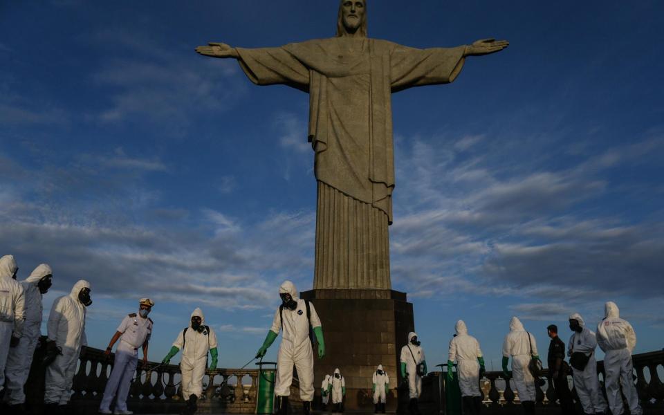 Pictured last year, military personnel in Rio disinfect the area around the Christ the Redeemer statue - Getty