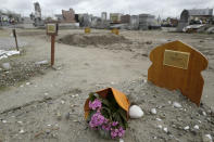 FILE- A bouquet of flower lays on the tomb of Yasser Abdallah, from Sudan, who died in an attempt to cross the English Channel in a truck on Sept. 28, 2021, in the Nord Cemetery of Calais, northern France, Thursday, Nov. 25, 2021. The price to cross the English Channel varies according to the network of smugglers, between 3,000 and 7,000 euros. Often, the fee also includes a very short-term tent rental in the windy dunes of northern France and food cooked over fires that sputter in the rain that falls for more than half the month of November in the Calais region. (AP Photo/Rafael Yaghobzadeh, File)