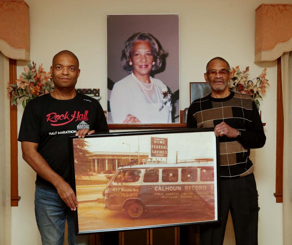 Homell Calhoun Jr., right, and his nephew Forrest Webb hold a photograph of a van promoting the Calhoun Record Shop, a record store started by Calhoun's parents, Homell Calhoun Sr. and Rebecca Calhoun, whose picture is on the mantel.