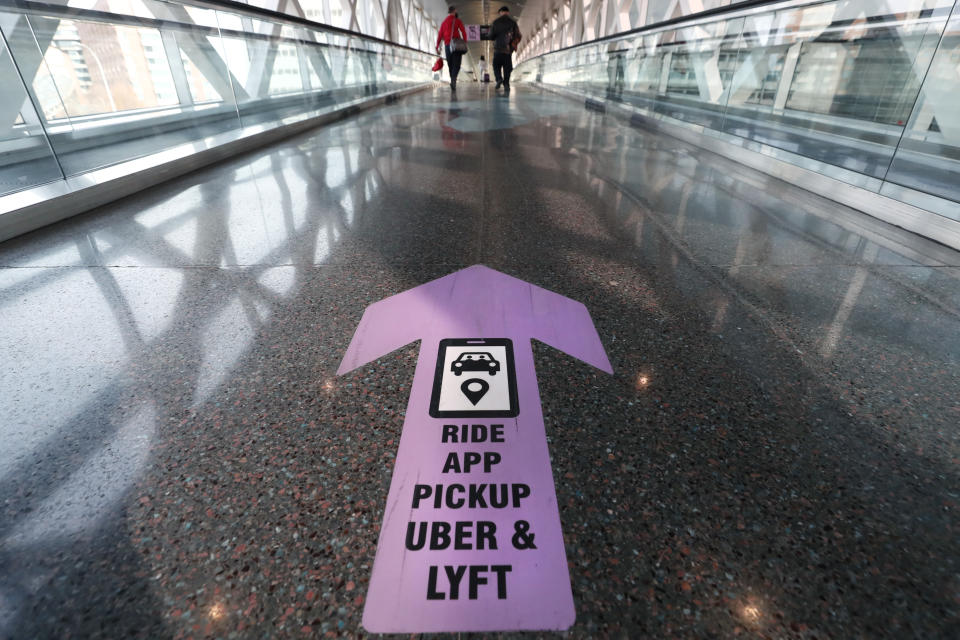 FILE - In this Nov. 20, 2020 file photo, travelers walk across a nearly empty skyway bridge towards the Uber and Lyft shared ride pick-up point at Logan Airport in Boston. Fresh off of their initial public offerings the year before and still struggling to show they can be profitable, the ride-hailing services were clobbered by the pandemic in 2020, as people stopped taking cars and huddled down at home. In May, Uber laid off 3,700 people, or about 14% of its workforce. Lyft also announced job cuts. (AP Photo/Michael Dwyer)