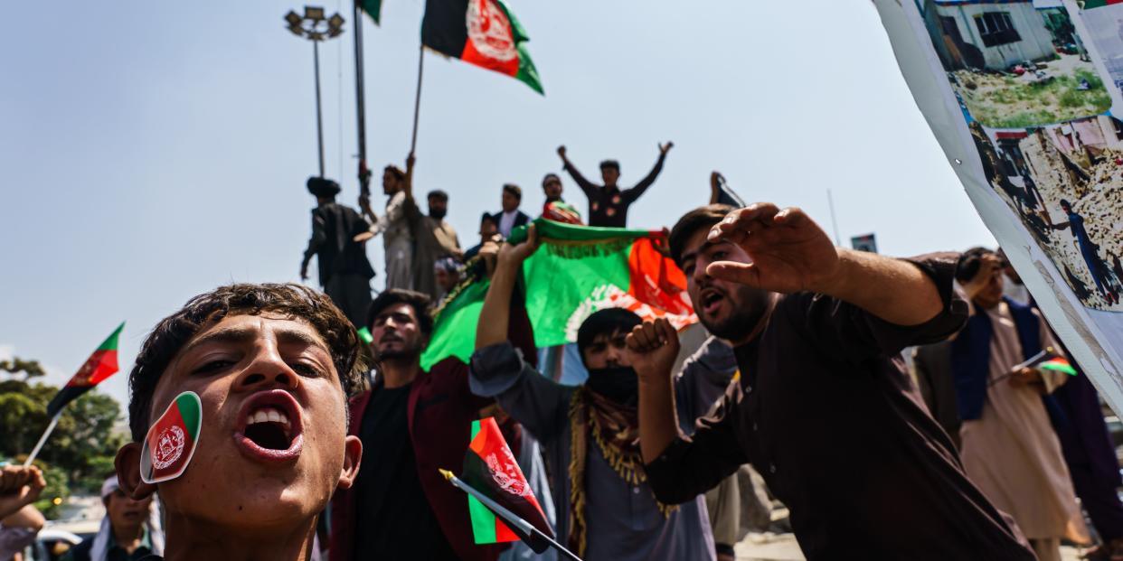 Afghans raise the national flag during a rally for Independence Day at Pashtunistan Square in Kabul, Afghanistan