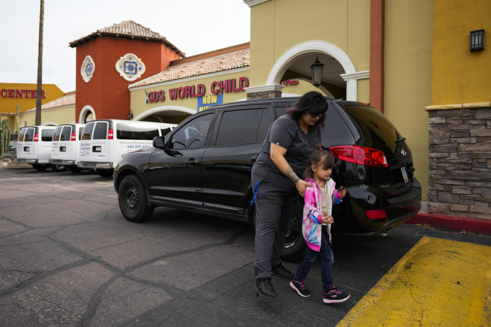 Vanessa Martinez helps her daughter, Janesa Wilford, 4, out of the car while dropping off her four children at daycare on Monday, March 20, 2023, in Chandler, Ariz. Martinez was shot in the head by her ex-boyfriend in September 2021, and was denied victim compensation due to unpaid court fines. (AP Photo/Ashley Landis)