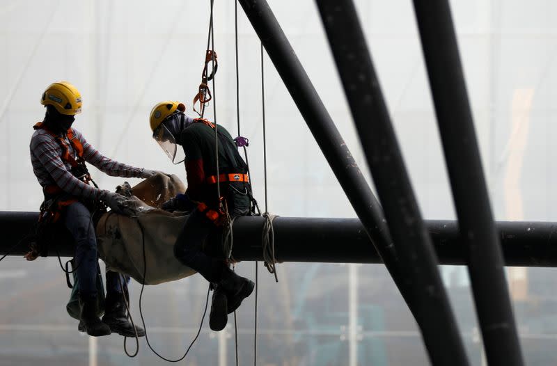 Construction workers are suspended on a steel beam at a work site in Singapore