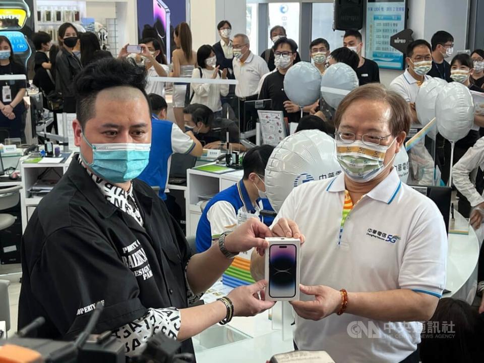 中華電信16日在台北東區服務中心舉辦iPhone 14新機首賣會，董事長謝繼茂（右）為首位排隊客戶許先生（左）加碼送出Hami Point 6600點。中央社記者吳家豪攝