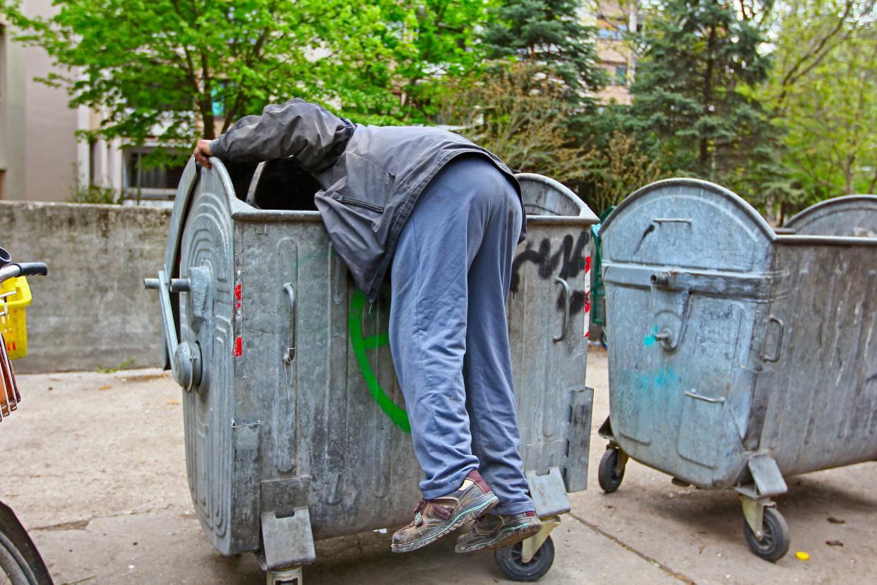 Homeless man is search for food in garbage