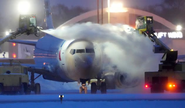 An American Airlines plane is de-iced as high winds whip around 7.5 inches of new snow at Minneapolis-St. Paul International Airport Thursday, Dec. 22, 2022. Temperatures plunged far and fast Thursday as a winter storm formed ahead of Christmas weekend, promising heavy snow, ice, flooding and powerful winds across a broad swath of the country and complicating holiday travel. (David Joles/Star Tribune via AP)