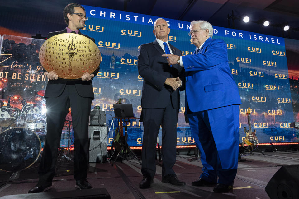 Republican presidential candidate former Vice President Mike Pence, center, is awarded the "Defender of Israel" award by Pastor John Hagee, right, Christians United For Israel (CUFI) Founder and Chairman, at a CUFI Night to Honor Israel event, during the CUFI Summit 2023, Monday, July 17, 2023, in Arlington, Va., at the Crystal Gateway Marriott. (AP Photo/Jacquelyn Martin)