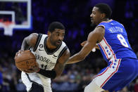 Brooklyn Nets' Kyrie Irving, left, tries to get past Philadelphia 76ers' De'Anthony Melton during the first half of an NBA basketball game, Wednesday, Jan. 25, 2023, in Philadelphia. (AP Photo/Matt Slocum)