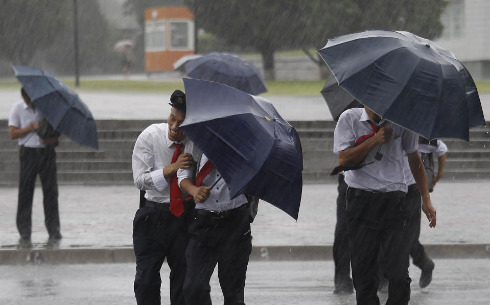 Pedestrians shield themselves from wind and rain brought by Typhoon Lingling Saturday, Sept. 7, 2019, in Pyongyang, North Korea. The typhoon passed along South Korea’s coast has toppled trees, grounded planes and caused at least two deaths before making landfall in North Korea. (AP Photo/Jon Chol Jin)