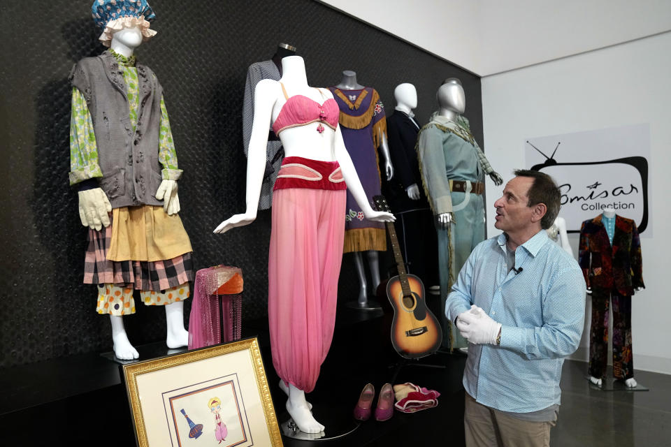 James Comisar responds to questions during an interview as he walks in front of a collection of outfits used by actors on famous television shows, Thursday, April 27, 2023, in Irving, Texas. A dizzying number of props, sets, and costumes from television shows beloved by generations of viewers will be sold at auction next month. The collection James Comisar has spent over 30 years amassing includes "The Tonight Show" set Johnny Carson gave him after retiring, the timeworn living room from "All in the Family," and the bar where Sam Malone served customers on Cheers. (AP Photo/Tony Gutierrez)