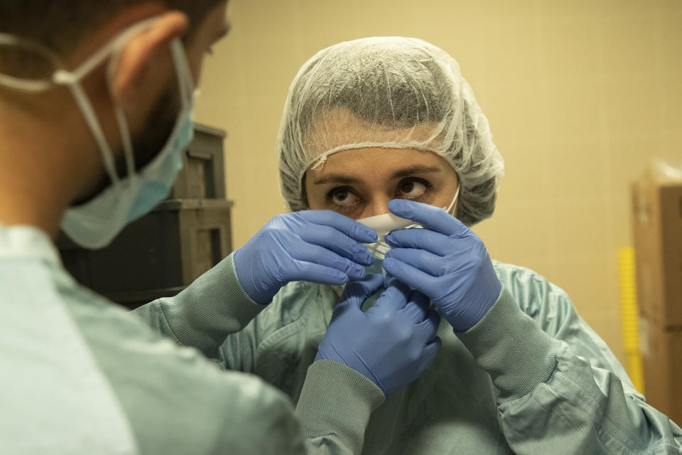 Dr. Pier Giorgio Pace helps his colleague Elisabetta Teti to wear protective suits before starting their first round medical examinations in a sub-intensive COVID-19 unit of the Tor Vergata Polyclinic Hospital, in Rome, Saturday, Nov. 7, 2020. (AP Photo/Alessandra Tarantino)