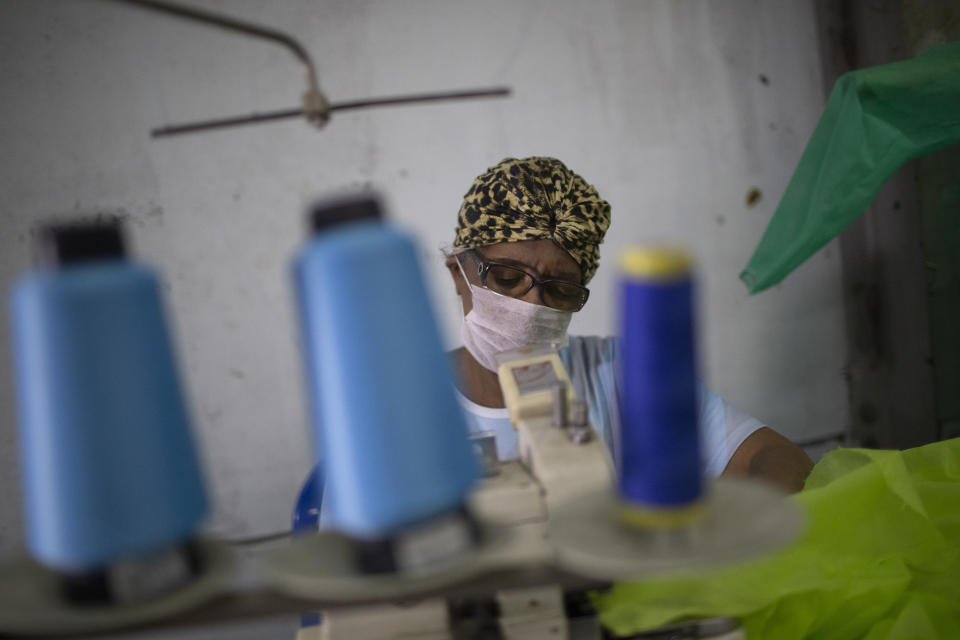 Jaqueline, de la escuela de samba Vila Isabel, cose trajes desechables para trabajadores sanitarios durante la pandemia del coronavirus, en Río de Janeiro, Brasil, el 7 de abril de 2020. Las escuelas de samba de Río de Janeiro suelen pasar el año cosiendo frenéticamente los disfraces para el impresionante Carnaval de la ciudad. Ahora, esos ágiles dedos trabajan para proteger vidas, elaborando trajes de protección para los empleados de salud que enfrentan una oleada de pacientes con coronavirus. (AP Foto/Silvia Izquierdo)