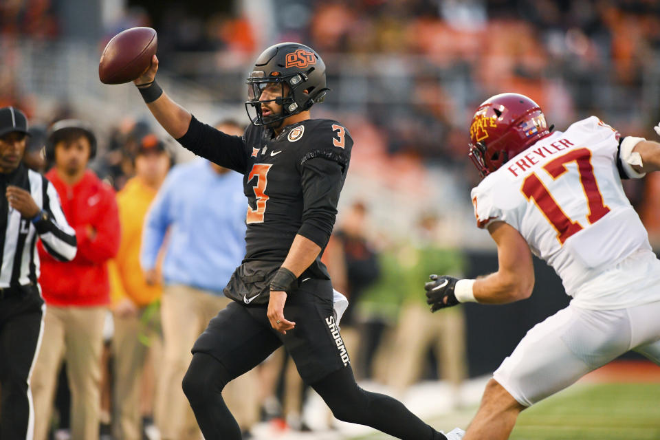 Oklahoma State quarterback Spencer Sanders (3) holds up the ball while running out of bounds under pressure from Iowa State defensive back Beau Freyler (17) during the second half of an NCAA college football game Saturday, Nov. 12, 2022, in Stillwater, Okla. (AP Photo/Brody Schmidt)