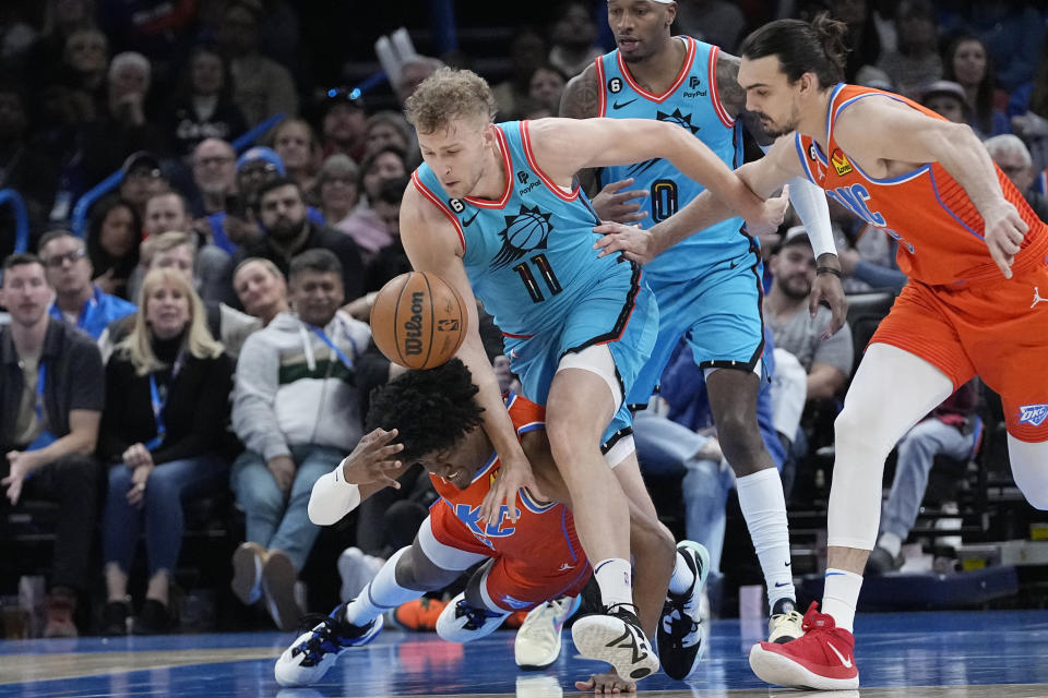 Phoenix Suns center Jock Landale (11) chases a loose ball with Oklahoma City Thunder forward Jalen Williams, left, and forward Dario Saric, right, in the second half of an NBA basketball game Sunday, March 19, 2023, in Oklahoma City. (AP Photo/Sue Ogrocki)