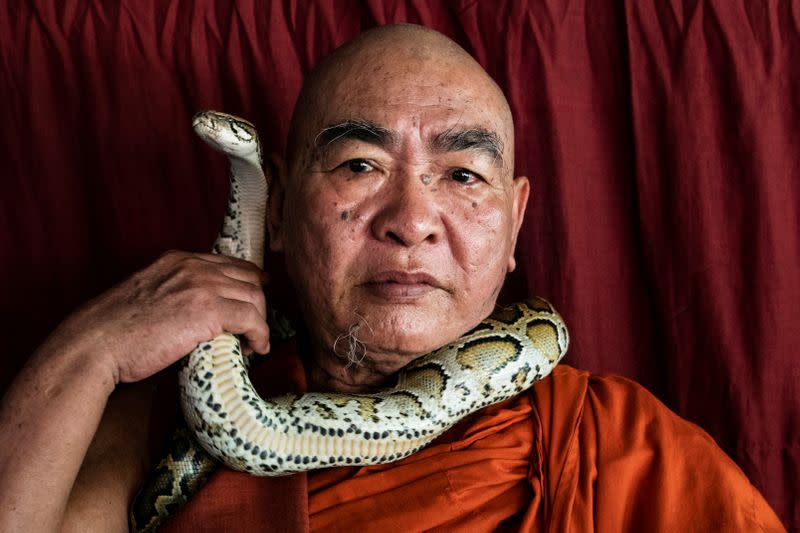 Buddhist monk Wilatha poses with a rescued Burmese python at his monastery that has turned into a snake sanctuary on the outskirts of Yangon, Myanmar