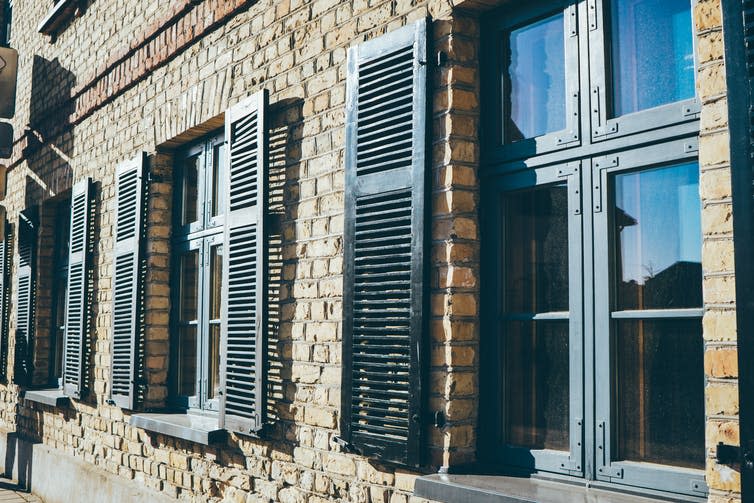 Black shutters adorn windows on a brick house.