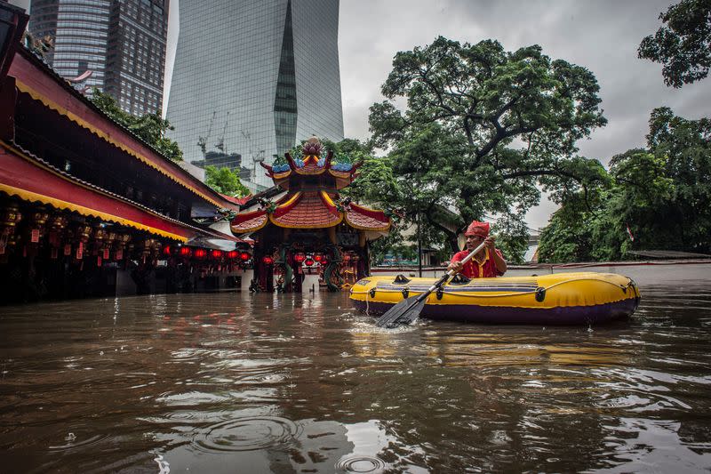 An elderly man uses an inflatable boat after floods hit his monastery in Jakarta