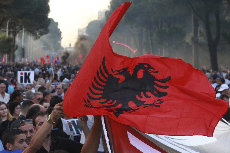 A demonstrator waves the Albanian national flag during an anti-government protest in Tirana, Albania, Saturday, June 8, 2019. Thousands of Albanian opposition supporters are gathering in an anti-government protest while the United States and the European Union caution their leaders to disavow violence and sit in a dialogue to overcome the political crisis. (AP Photo/Hektor Pustina)